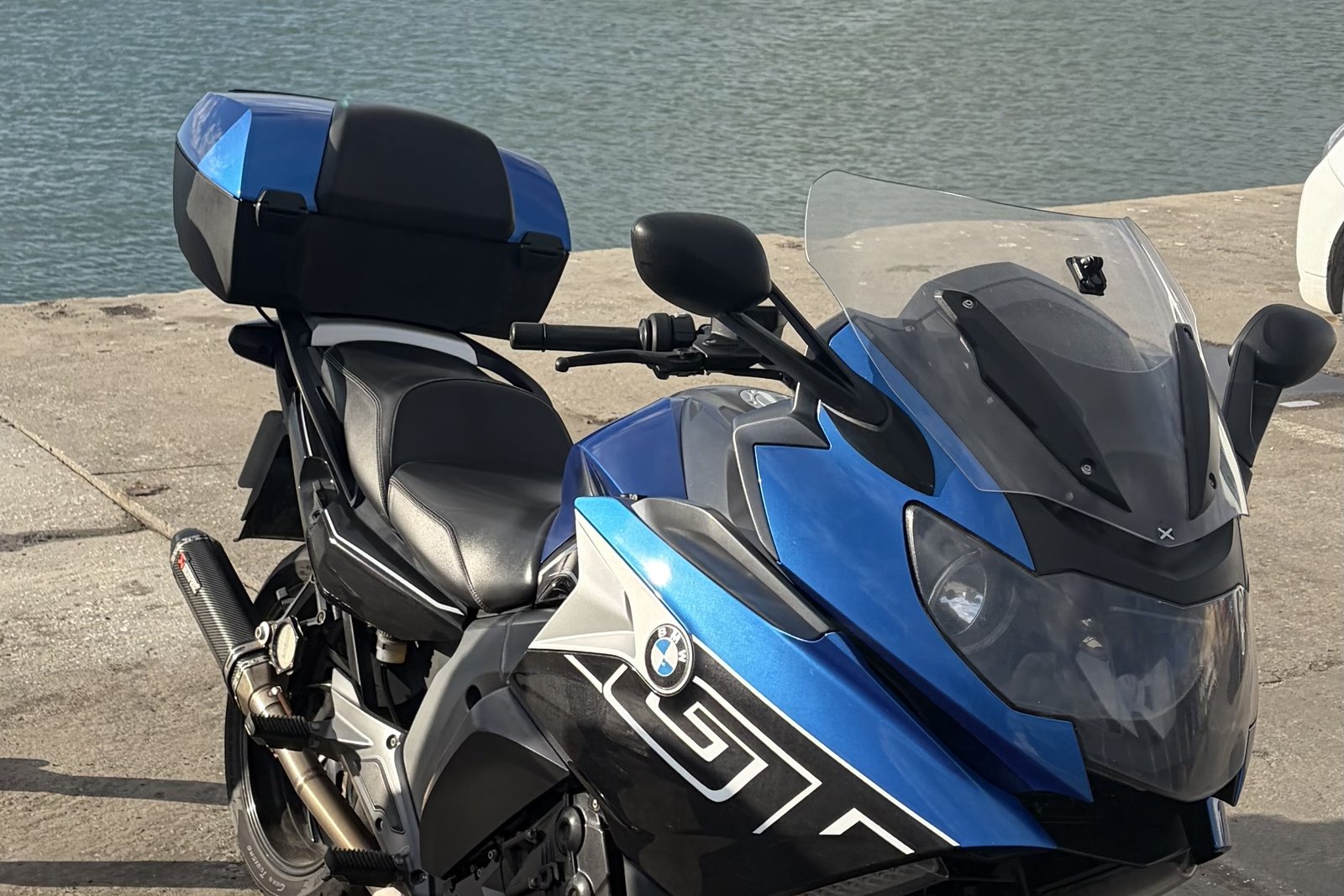 A BMW K1600 GT parked on a harbour quayside on South Africa's West Coast, with calm water beyond.